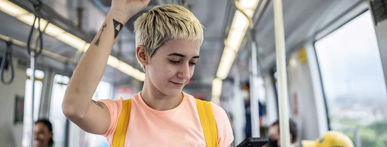 Jovem profissional vê o celular enquanto faz o caminho até o trabalho 