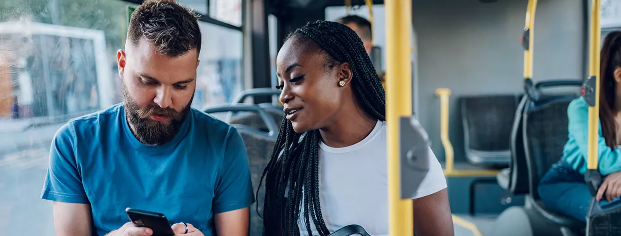Dupla de amigos confere as notícias enquanto vão para o trabalho de ônibus 