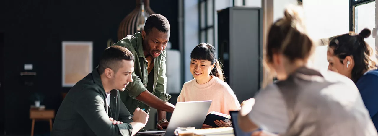 Foto mostra uma equipe com pessoas de diversas origens trabalhando juntas 