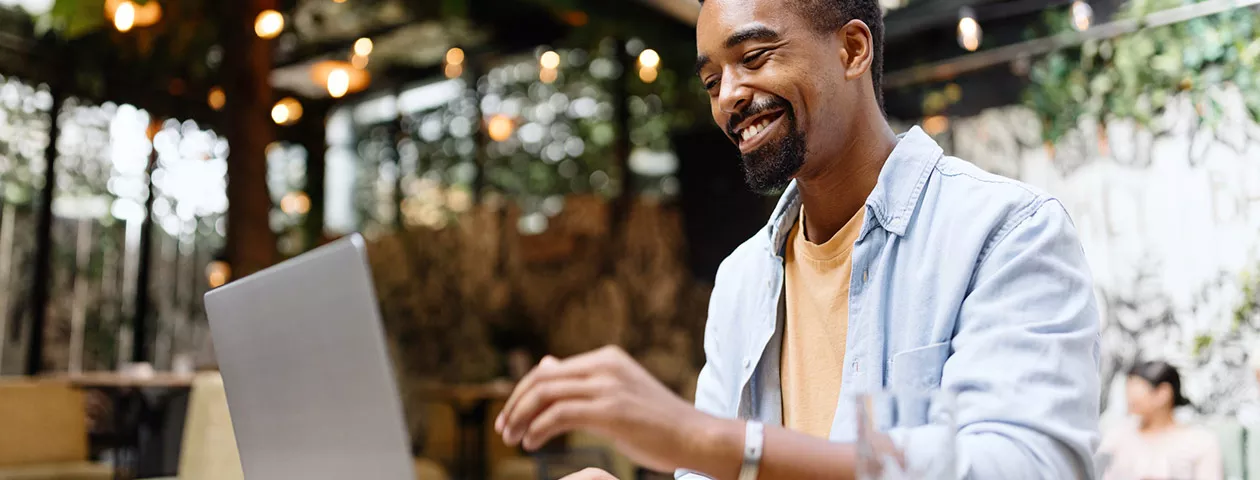 Homem trabalha no seu computador e sorri 