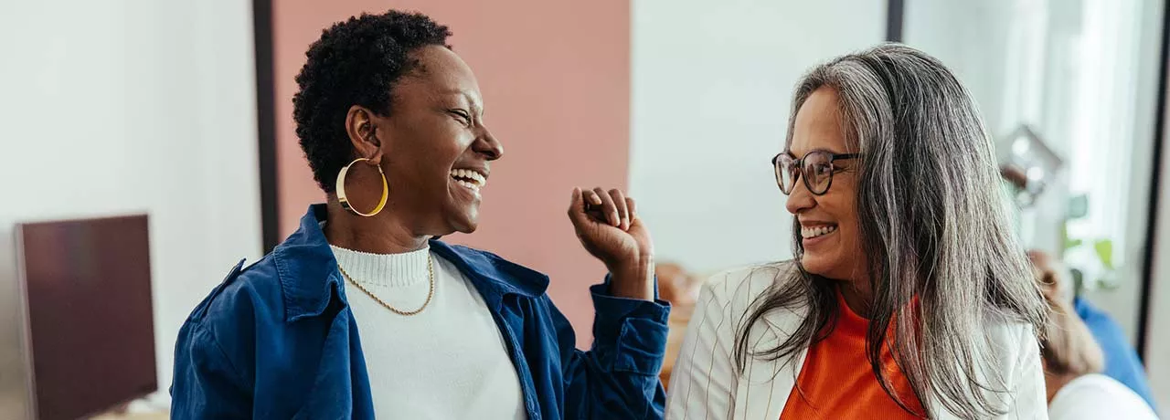 Duas colegas de trabalho conversam animadas durante o expediente 