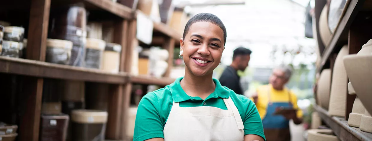 Foto mostra funcionária de uma loja de cerâmicas sorrindo para a câmera 