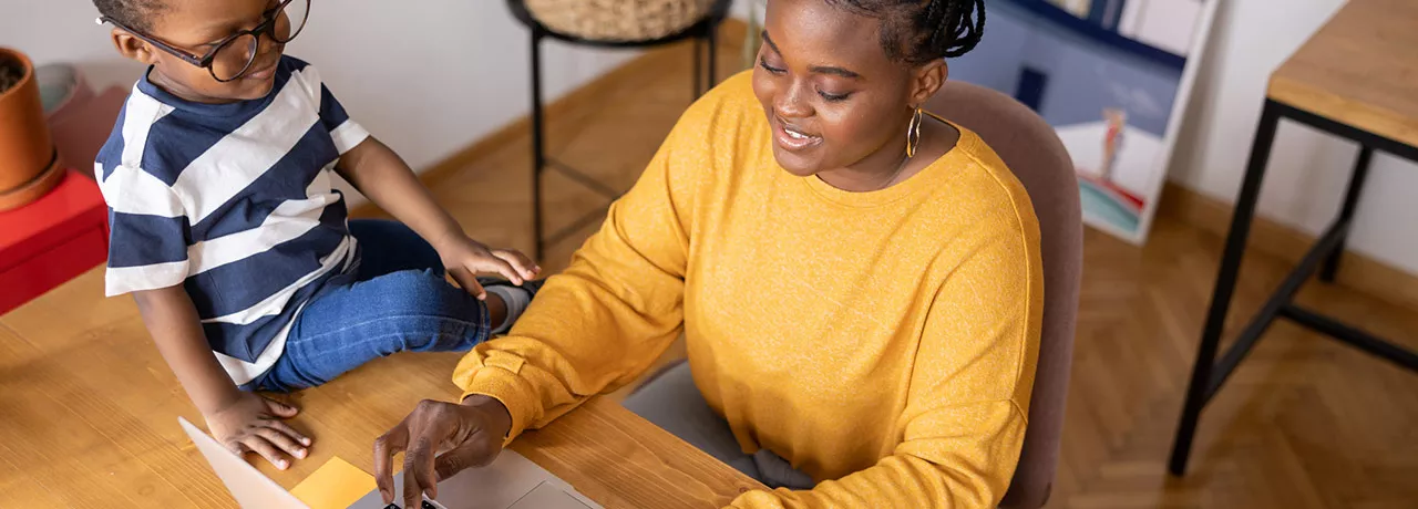 mulher trabalhando de home office com filho ao lado. 