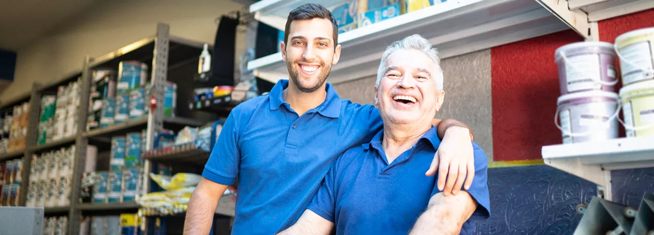 dois homens de diferentes idades sorrindo no trabalho. 