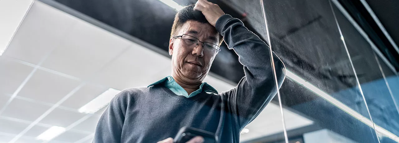 pessoa olhando o celular no trabalho com expressão de preocupação. 