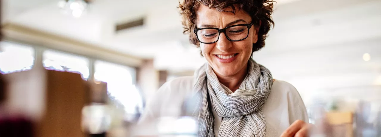 A imagem mostra uma mulher de óculos se alimentando em um restaurante 
