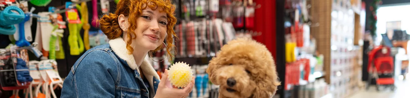 Jovem profissional compra brinquedo para seu cachorro com seu benefício flexível da empresa. 