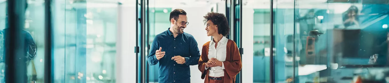 duas pessoas conversando em corredor de escritório.