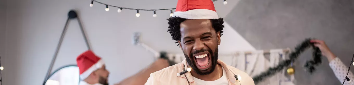 Foto mostra colegas de trabalho animados ao fazer a decoração de natal no escritório 