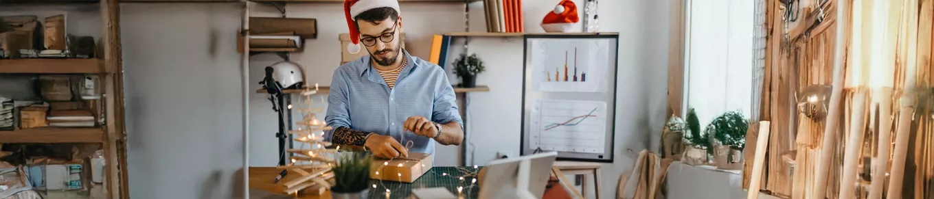 Funcionário em home office desembala um presente de Natal da empresa 