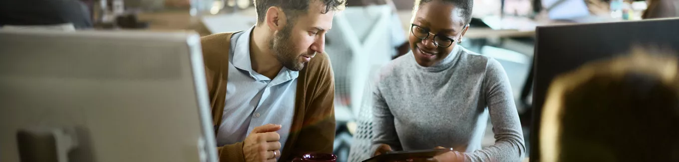 duas pessoas conversando enquanto olham algo em tablet.