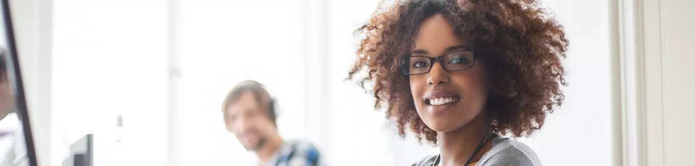 mulher sorrindo para a câmera em ambiente de trabalho. 