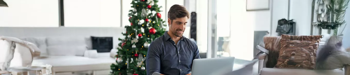 homeme trabalhando com árvore de natal atrás. 