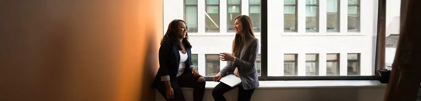 Foto mostra duas pessoas conversando em uma sala de reunião 