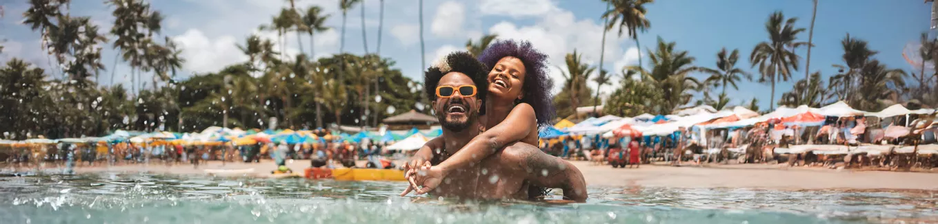 Foto mostra um casal curtindo férias na praia