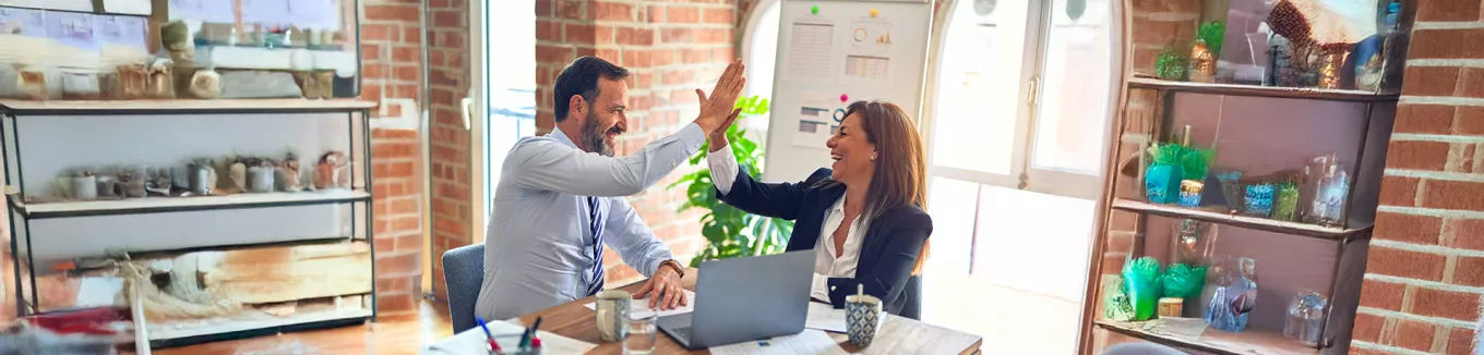 duas pessoas fazendo "toca aqui" no trabalho. 