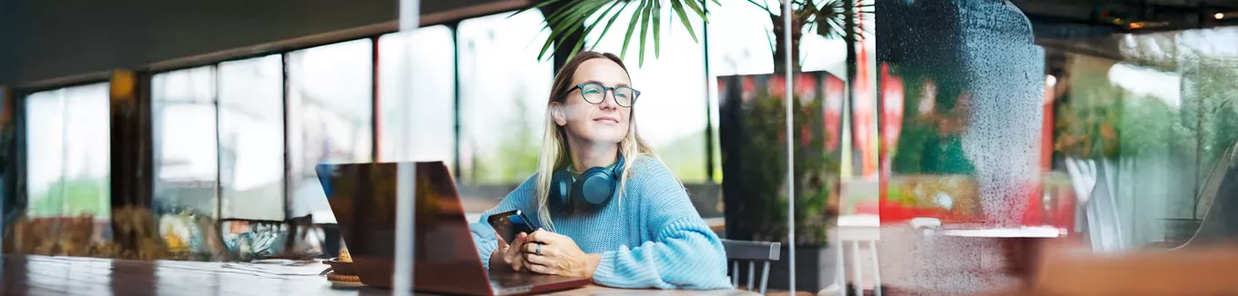 Foto mostra uma pessoa trabalhando em um notebook em uma sala ampla 