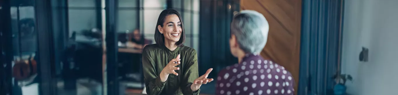 duas mulheres conversando em um ambiente corporativo  