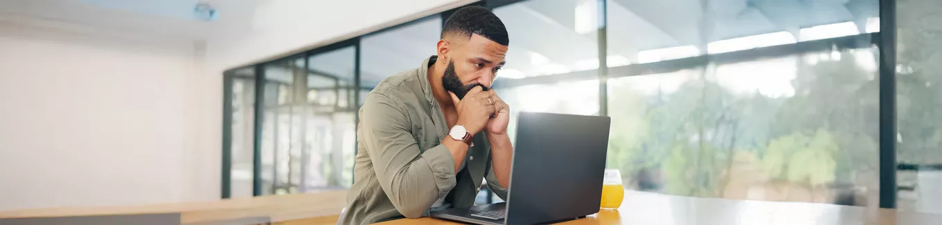 Foto mostra um homem preocupado olhando para seu notebook no escritório 