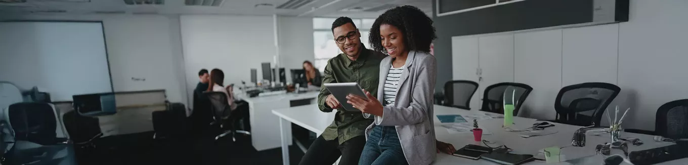 duas pessoas olhando informação em tablet no escritório. 