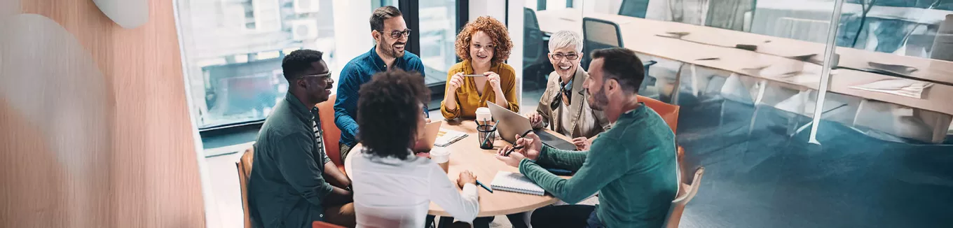time conversando em torno de uma mesa dentro de escritorio. 