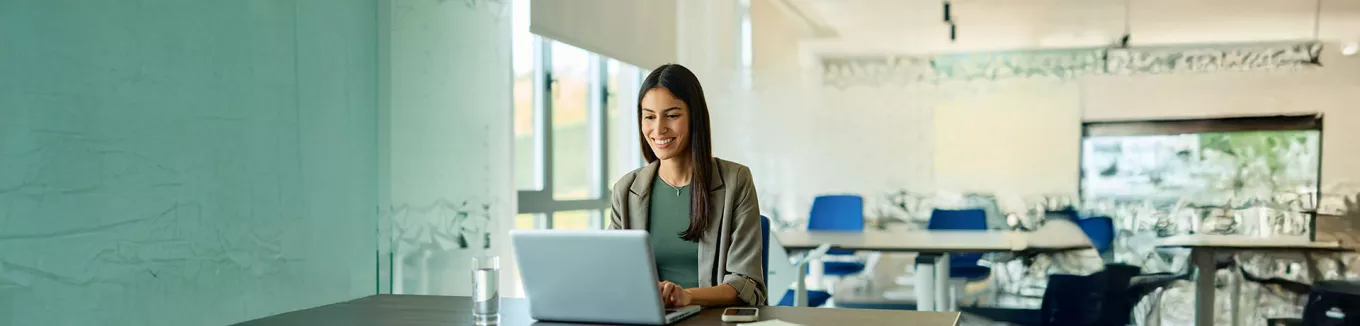 mulher sorrindo enquanto usa o computador no trabalho. 