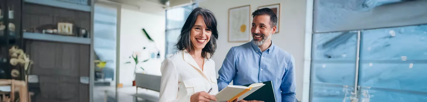duas pessoas sorrindo no ambiente de trabalho. 