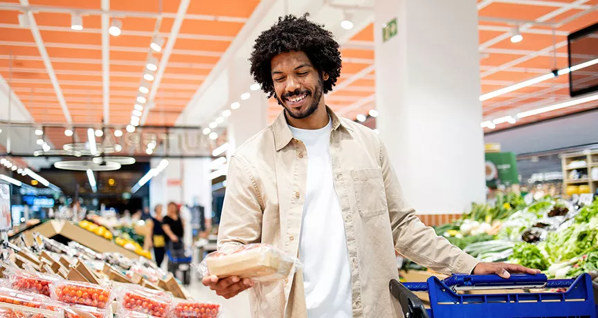 Foto mostra um homem comprando alimentos frescos no supermercado com seu Pluxee Alimentação
