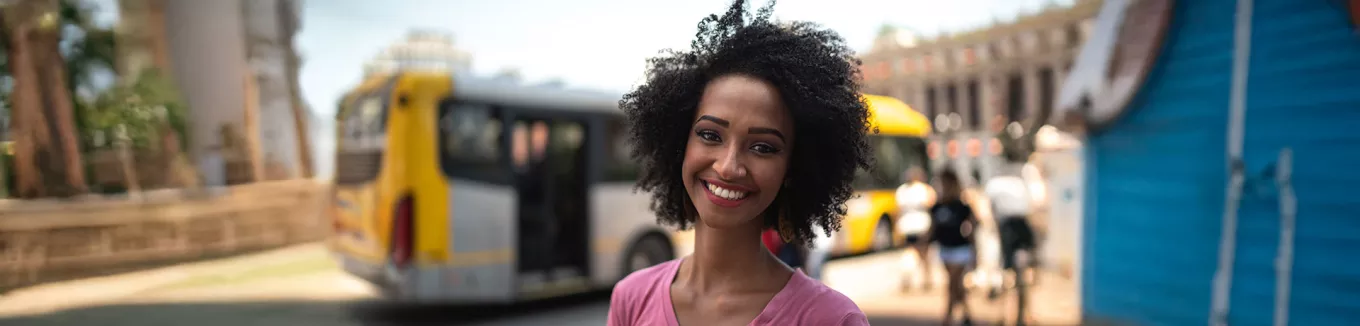 mulher sorrindo em frente a onibus. 