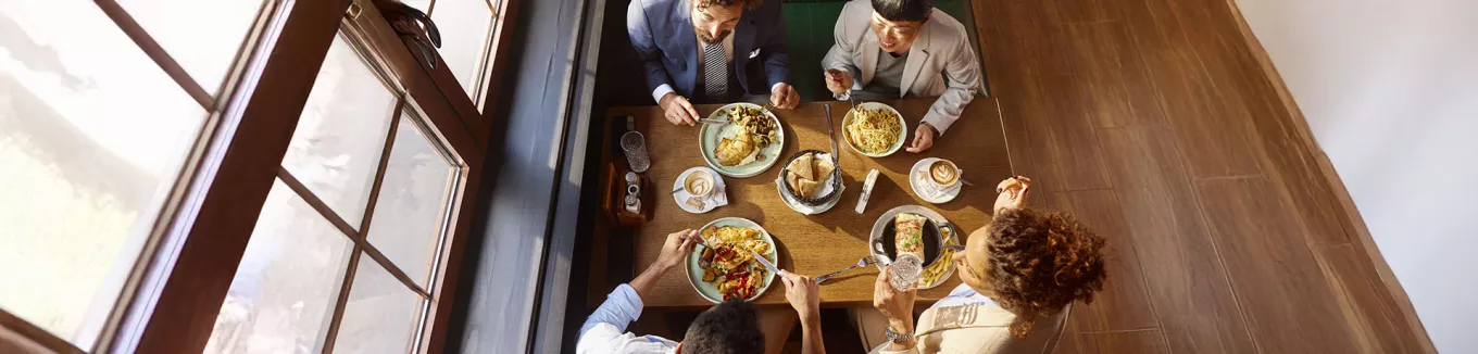 visão aérea time almoçando junto em mesa. 