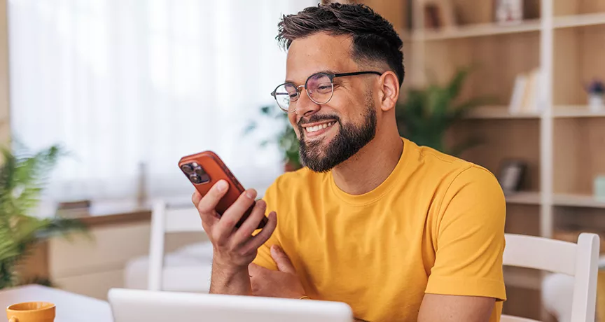 homem sorrindo para algo no celular. 