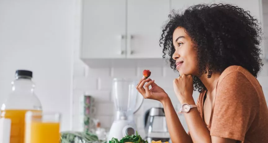 mulher olhando pela janela com um morango na mão