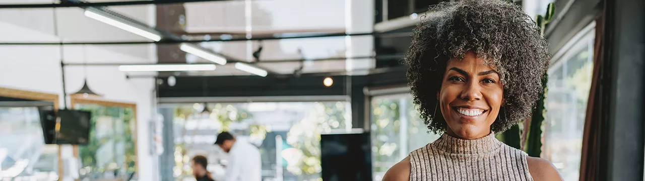 Empreendedora sorri para a câmera, mostrando seu salão de beleza