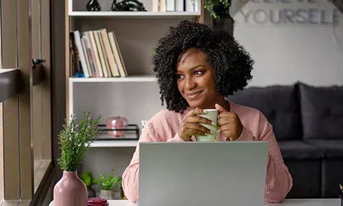 Mulher trabalha feliz no regime de home office. O que leva à felicidade no trabalho?