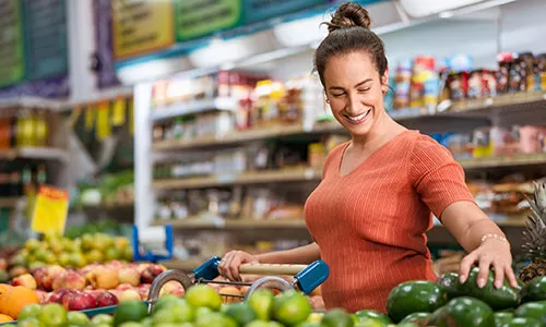 Mulher compra frutas no supermercado com seu vale-alimentação