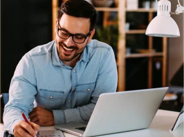Foto mostra um homem trabalhando em sua mesa de trabalho