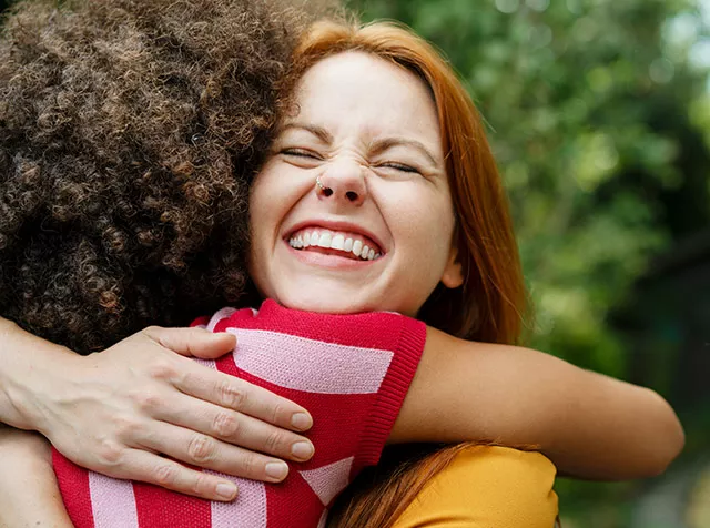 Duas amigas se abraçam felizes no parque