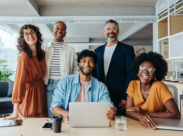 Foto mostra um grupo de trabalho feliz