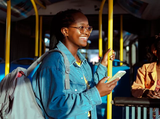 Pessoas em transporte publico usando smartphone, representando dados de infográfico de mobilidade em estudo Pluxee sobre deslocamento urbano.