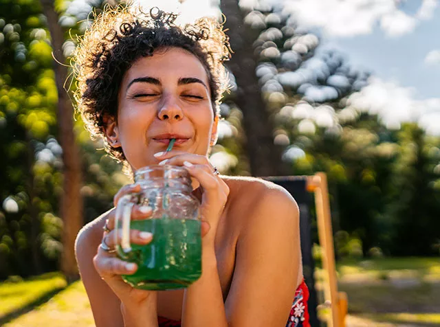 Mulher toma um suco feito com alimentos frescos que ela comprou com vale-alimentação