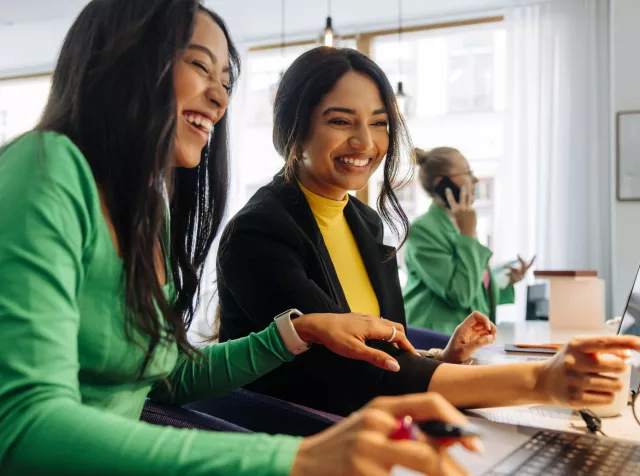 Profissionais colaborando em frente ao computador durante atividade de equipe, tema abordado na pesquisa Pluxee + Ipsos 2026 sobre engajamento no trabalho