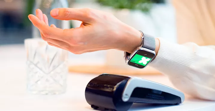 Tecnologias do futuro do varejo sendo ilustradas por uma mulher pagando sua conta usando seu smartwatch