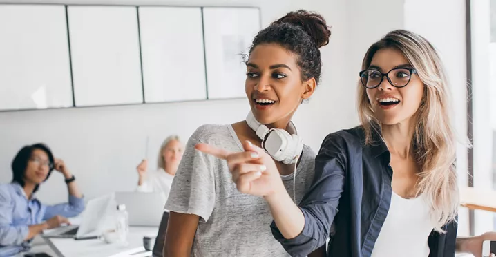 Duas colegas de trabalho conversam no escritório
