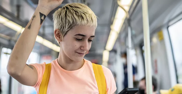 Jovem profissional vê o celular enquanto faz o caminho até o trabalho
