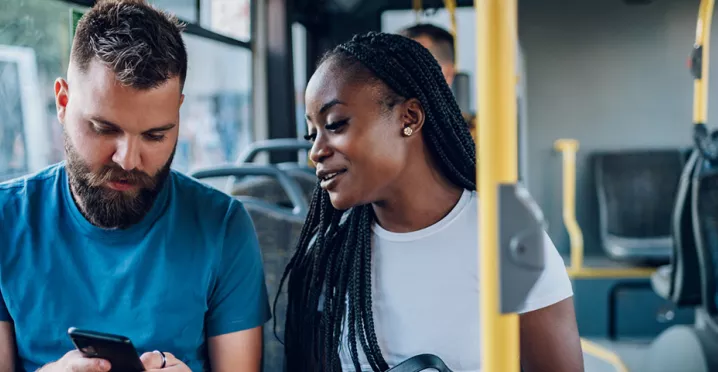 Dupla de amigos confere as notícias enquanto vão para o trabalho de ônibus
