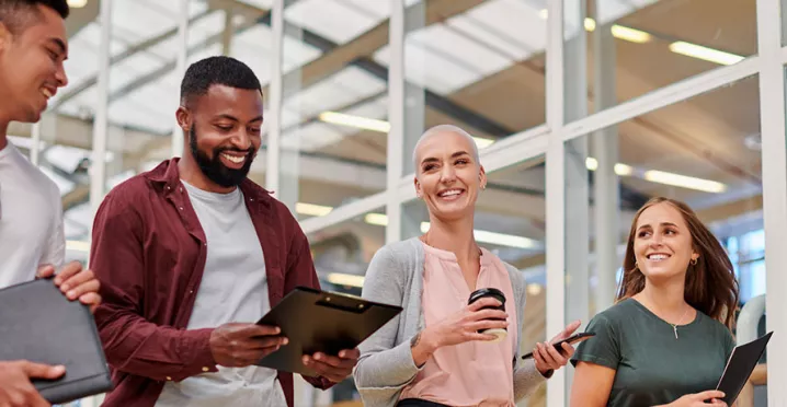 Na foto, quatro jovens profissionais conversam animados depois de uma reunião importante