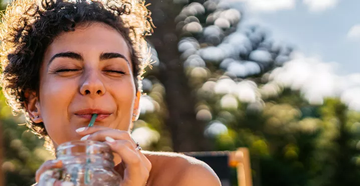 Foto mostra mulher tomando um suco em um parque