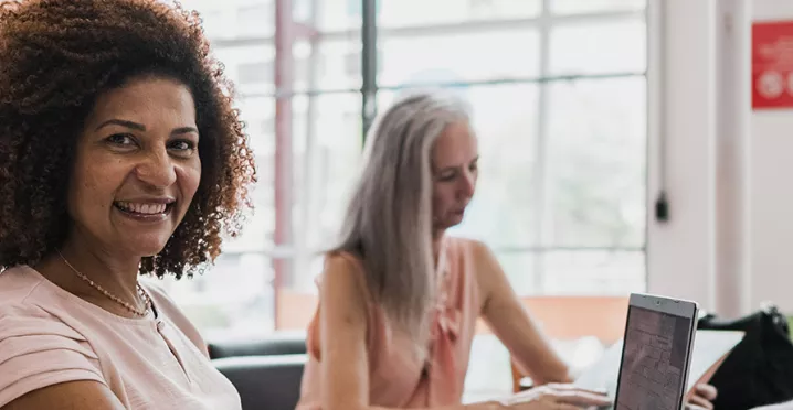 Mulher sorri para a câmera em um ambiente de trabalho com diversidade e inclusão