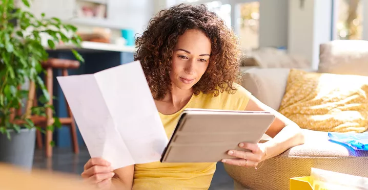 Mulher analisa documentos na sala da sua casa