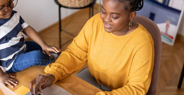 mulher trabalhando de home office com filho ao lado.